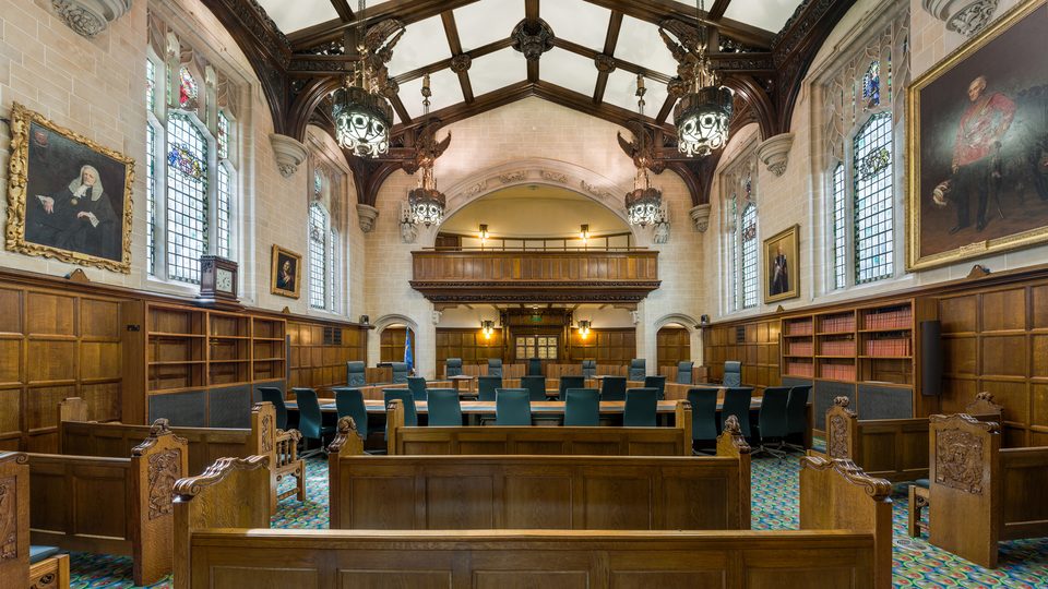 Court 1 of the Supreme Court of the United Kingdom, a wood panelled courtroom with green carpet and portraits on the walls