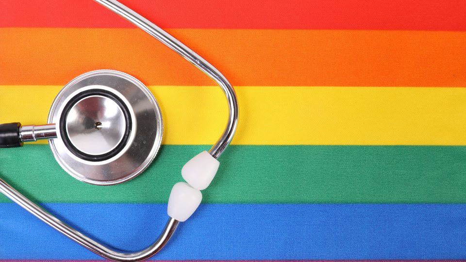 A stethoscope lying on a rainbow striped background