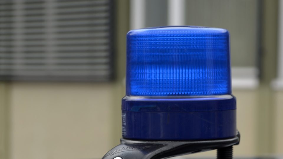 A blue emergency beacon mounted on the dark roof of an unmarked police car