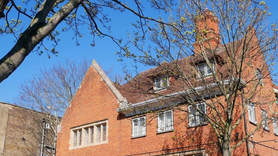 The red brick Coroner's Court in Poplar, east London, seen through spring branches against a deep blue sky
