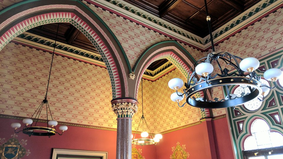 The painted room in the Royal Courts of Justice, with patterned walls in red and gold and an iron chandelier
