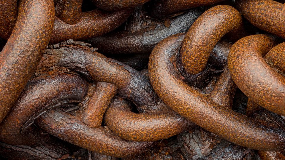 Close up of heavy, rusted iron chain links glistening in the rain