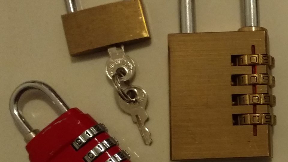 Three padlocks, one red and two brass, laid out with a pair of keys