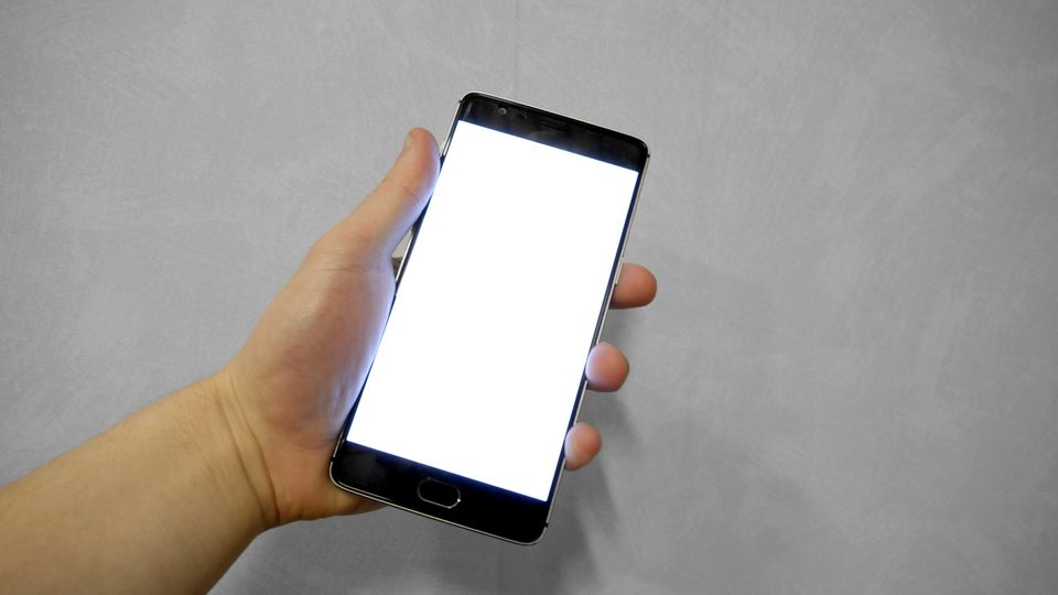 A hand holding a smartphone with a blank white screen
