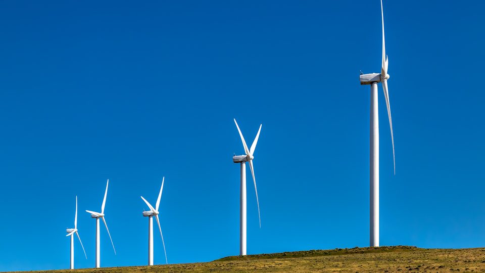 White wind turbines on a ridge above the Columbia River under a deep blue sky