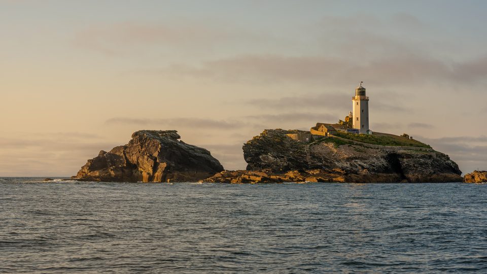 Godrevy Lighthouse on its rocky island off the Cornish coast in warm evening light