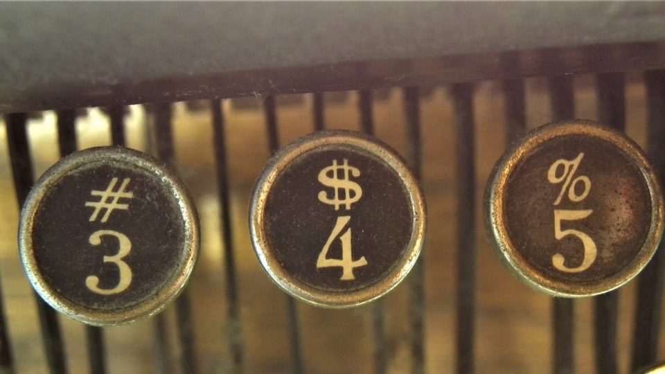 Three round typewriter keys marked with numbers and symbols, close up